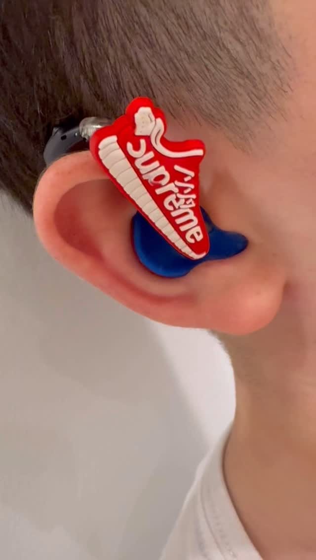 A red sneaker charm on a hearing aid