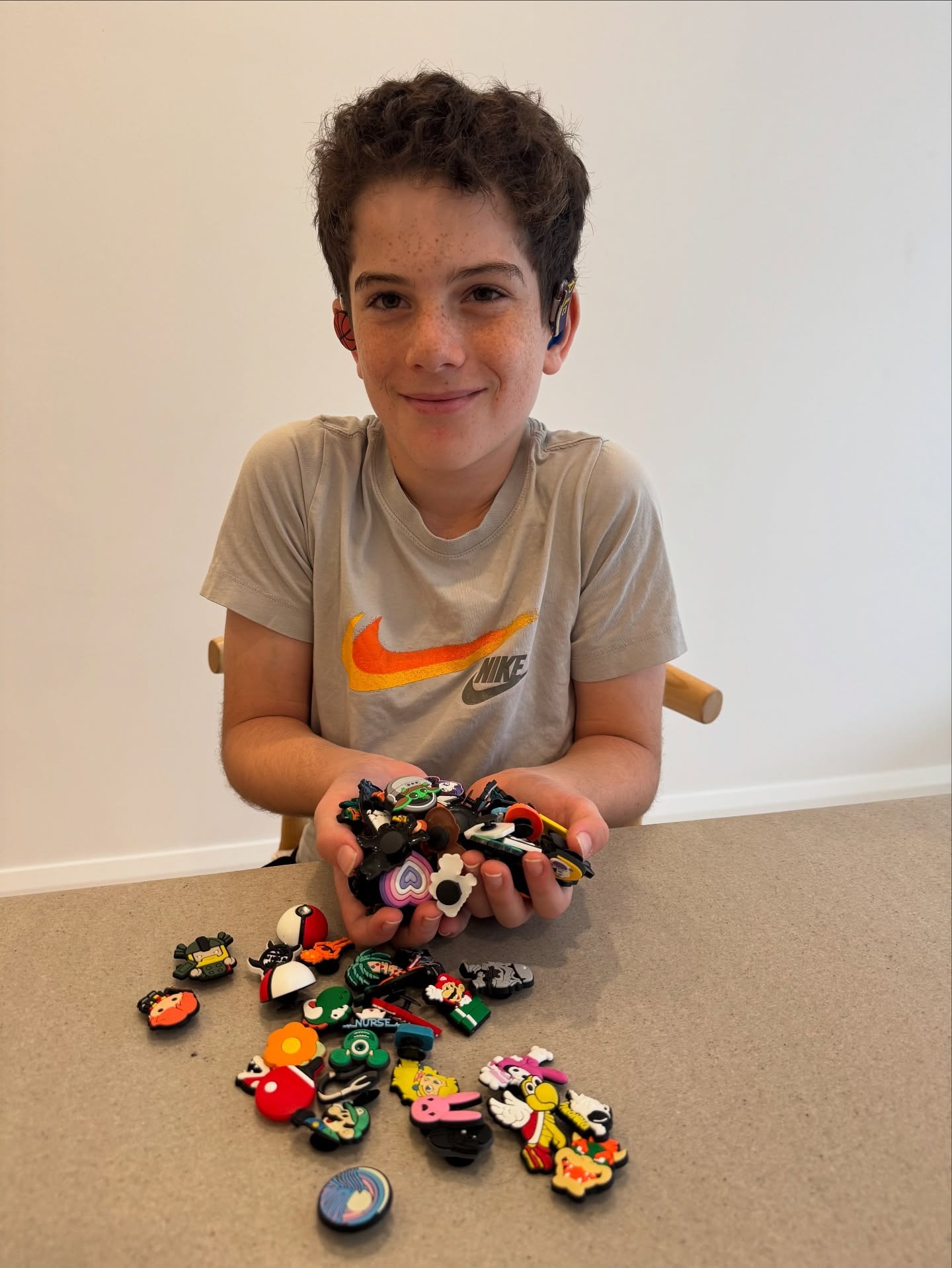 Eden holding a handful of charms, with more spread on the table
